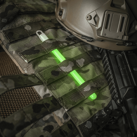 M-Tac Glow Stick 15 cm placed on military equipment, non-toxic and versatile light stick for safety and emergency situations.