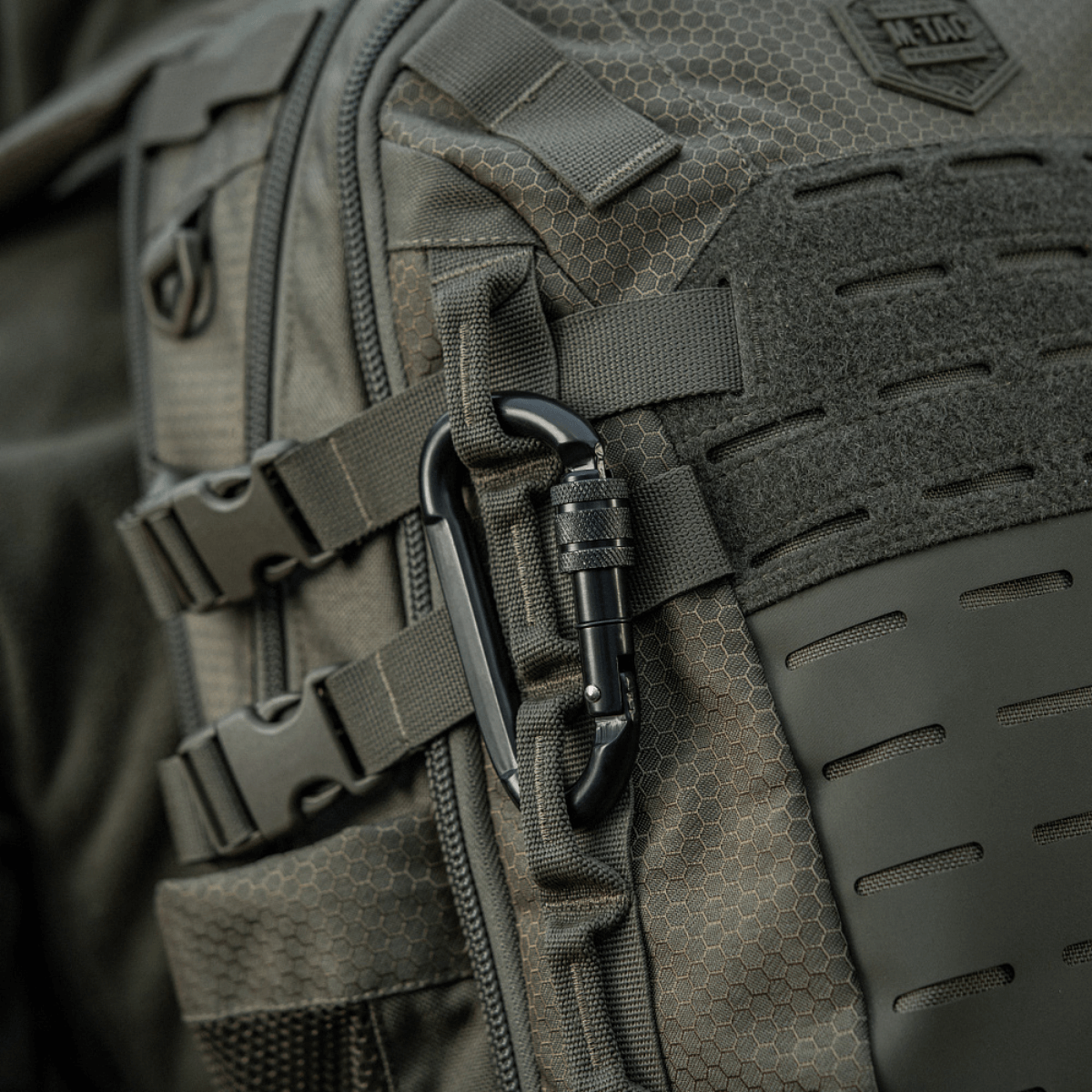 M-Tac Karabinhage 10 cm fastgjort til en rygsæk, lavet af holdbart 40Cr legeret stål, ideel til reb og slynger.