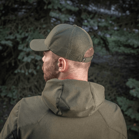 Mand iført M-Tac Mesh Flex Ripstop Baseball Cap i skovmiljø, viser mesh-paneler og Velcro-strop. Perfekt til udendørs aktiviteter.