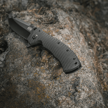 M-Tac Outdoor & Military folding knife - Type 7 on rock, lightweight design, black blade in chrome stainless steel, frame-lock mechanism.