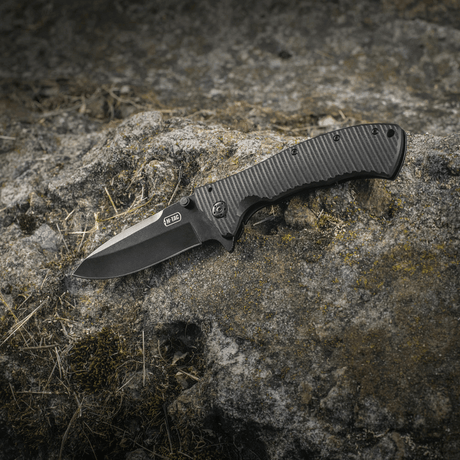 M-Tac Outdoor & Military folding knife - Type 7 in black coating on a rock background.