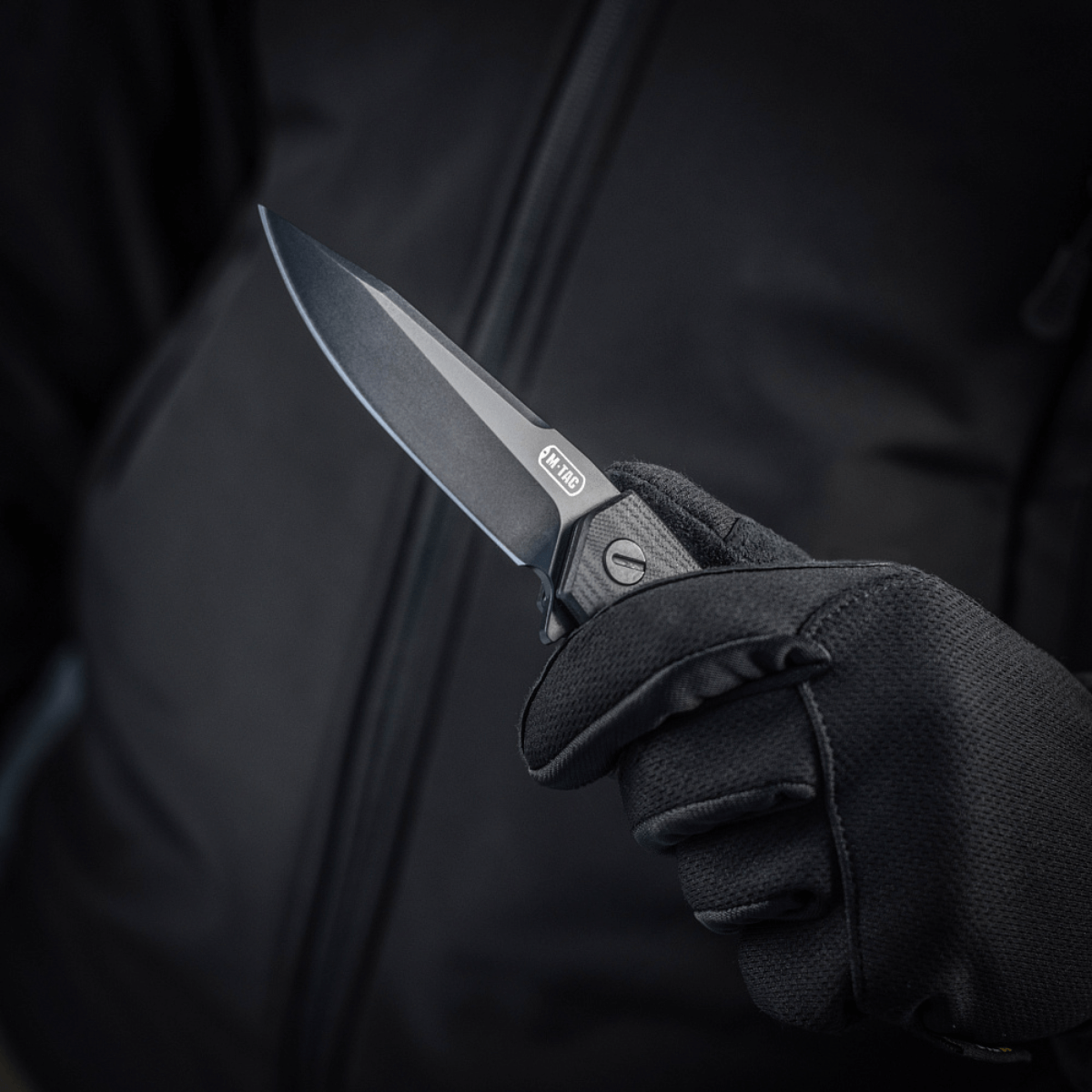 M-Tac Outdoor & Militær foldekniv - Type 6 holdt i en hånd iført sort handske, krom rustfrit stål klinge, G10-komposit håndtag.