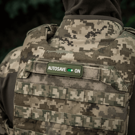 M-Tac Patch Autosave PVC on military vest with camouflage print, 3D morale patch with Velcro backing for easy attachment.