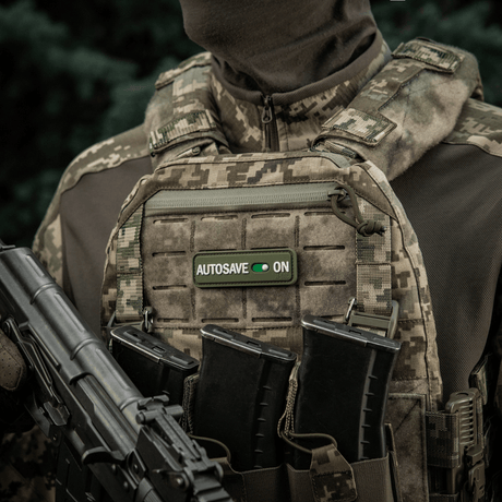 Soldier wearing a military vest with M-Tac Patch Autosave PVC with 3D effect, Velcro and full color for tactical use.