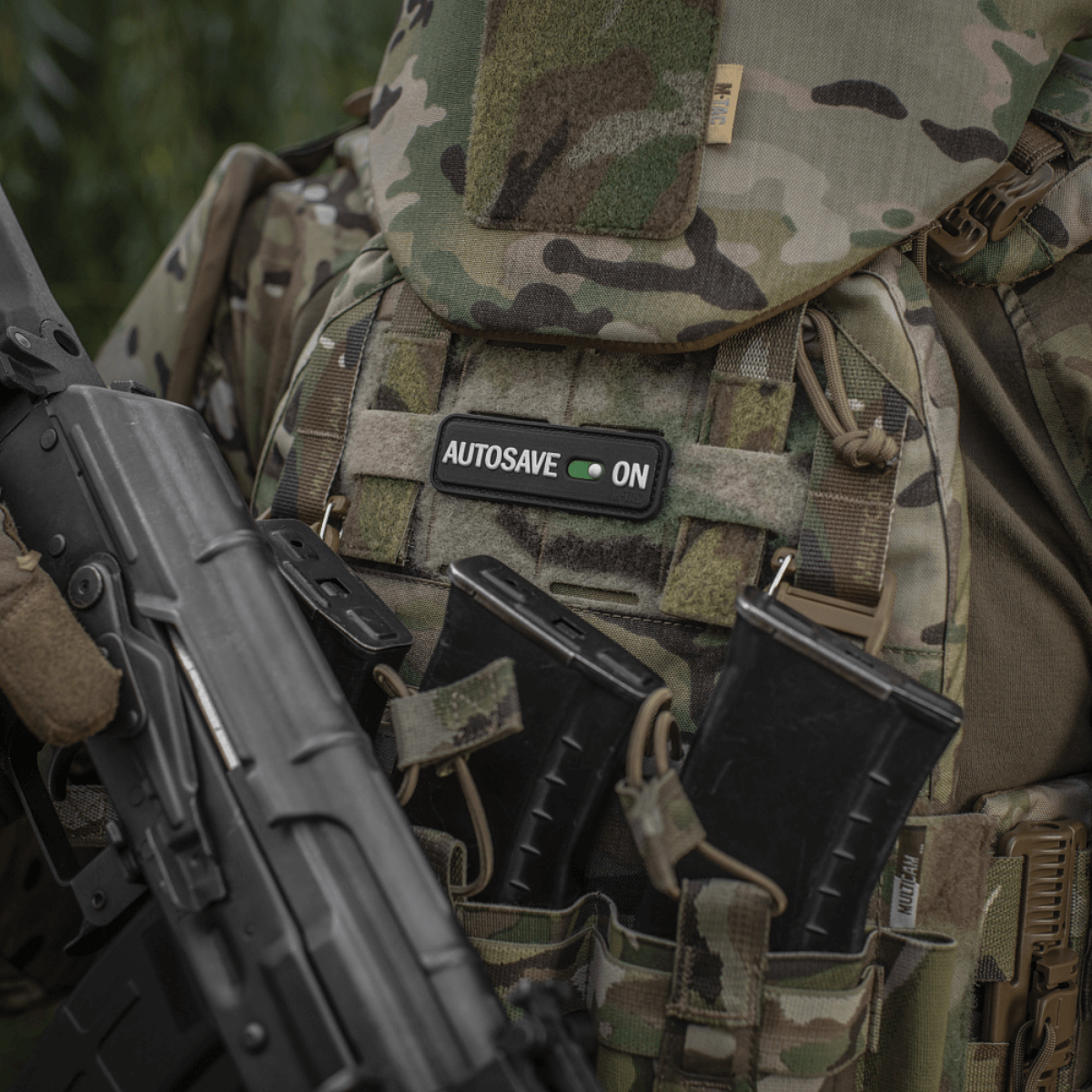 M-Tac Patch Autosave PVC på en camouflagejakke med magasinlommer, der viser detaljeret 3D-design og farveklarhed, ideel til taktisk brug.