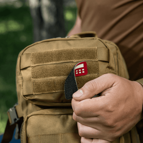 M-Tac Patch Flag 25x80 Mini Squares on a bag, held by a person. Cordura 500D, Velcro mounting, laser cut, durable and lightweight patch.