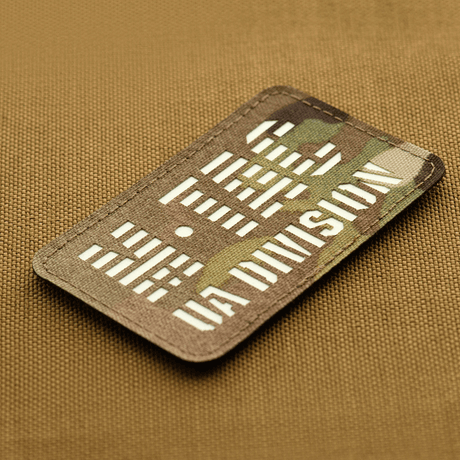 M-Tac Patch UA Division Laser Cut with glow-in-the-dark material and Velcro, made of Cordura 500D, on brown background.