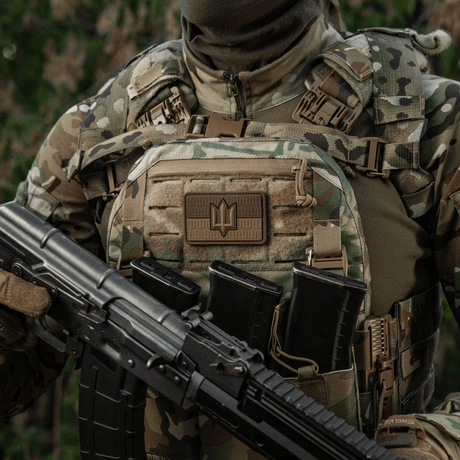 Soldier wearing a camouflage vest with M-Tac Ukraine Flag patch with ZSU Trident PVC, holding a rifle, symbolizing Ukrainian pride and heritage