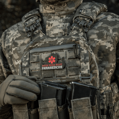 Tactical vest with attached patch, 'Odin Vils Make Paramedicine', in camouflage pattern.