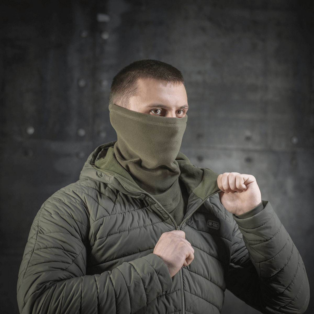 Mand iført M-Tac Polartec Anatomic Tube Scarf som ansigtsmaske i grønt miljø.