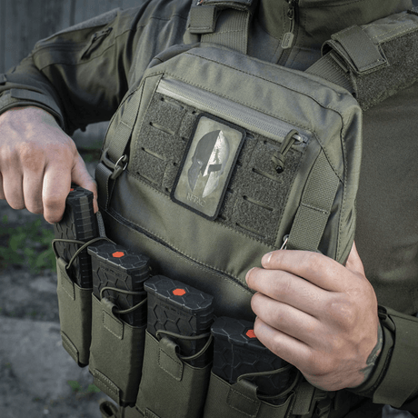Man wearing M-Tac Spartan Helmet Patch, Cordura 500D, on a military vest, shows courage and strength with Velcro fastening, vintage look.