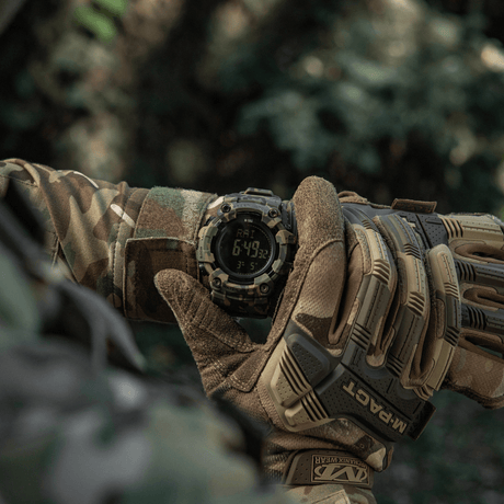 M-Tac Tactical Watch 2037 in use in nature, shown on wrist of person in camouflage clothing, showing LED-backlit display and features.