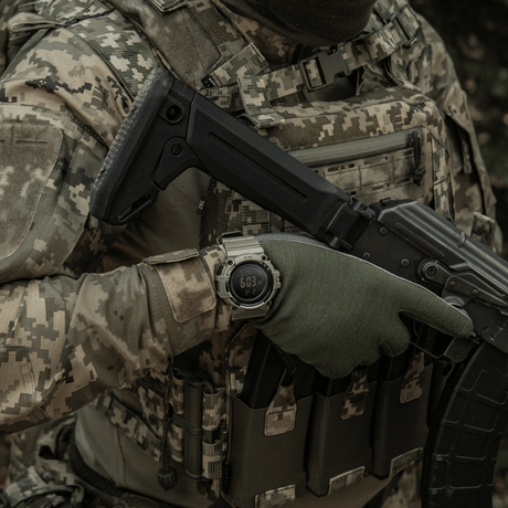 Person in camouflage clothing wearing M-Tac Tactical Watch with Compass 2233 in a military setting.