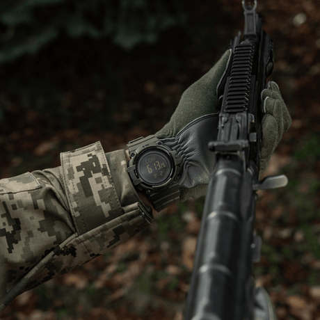 M-Tac Tactical Watch with Compass 2233 worn by a person in camouflage with a rifle, showing durability and functionality in the wilderness.