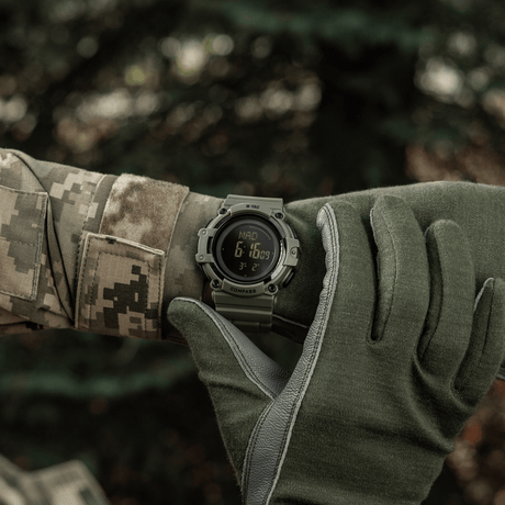 M-Tac Tactical Watch with Compass 2233 worn by a soldier outdoors, showing rugged design and features such as LED lighting and 5ATM water resistance.