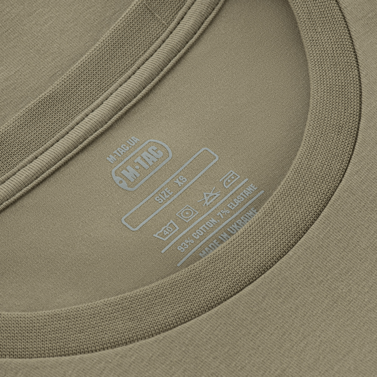 Nærbillede af M-Tac T-Shirt Talpa etiket, viser størrelse og materialeoplysninger. Perfekt blanding af komfort og stil.