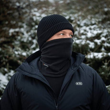 Mand iført M-Tac Tube Scarf Polartec i sneklædt landskab, beskyttet mod kulde med multifunktionel halstørklæde og jakke.