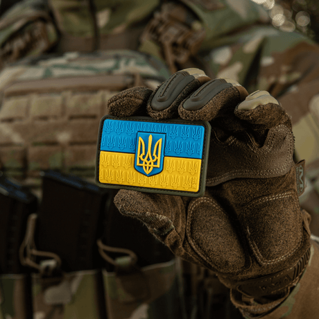 M-Tac Patch Ukraine Flag with coat of arms in PVC with 3D Trident, held by a person in military camouflage clothing.