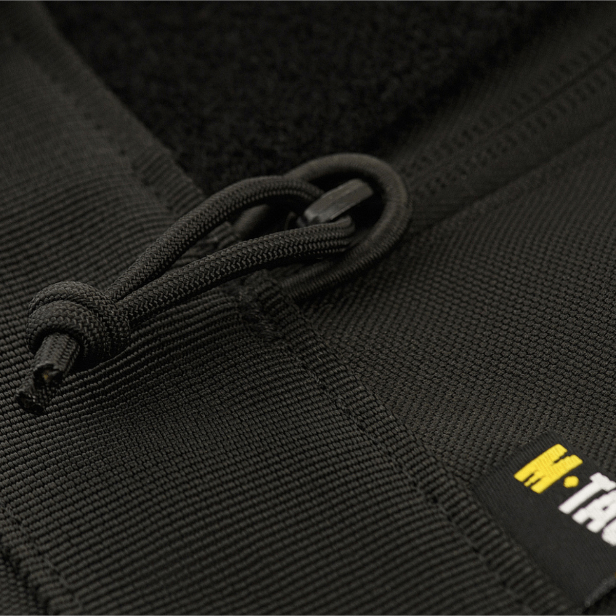 Sort lynlås detalje på M‑Tac Våbenetui 128 cm, et polstret transportetui med velcrostropper til sikker våbenopbevaring.