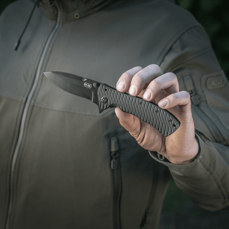 Person holding M-Tac Outdoor & Military folding knife - Type 7 with black blade and ergonomic grip, ideal for tactical use.