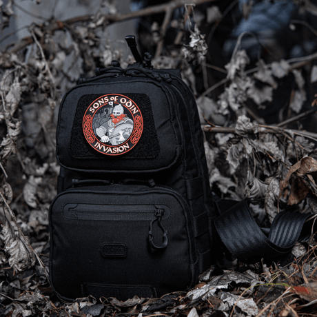 Black backpack with M-Tac Patch Sons of Odin 3D Velcro in a woodland area, suitable for tactical use and leisure