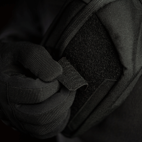 Person wearing black glove adjusts M-Tac Patch Valknut Laser Cut Odin symbol on a jacket. Tactical gear with Velcro.