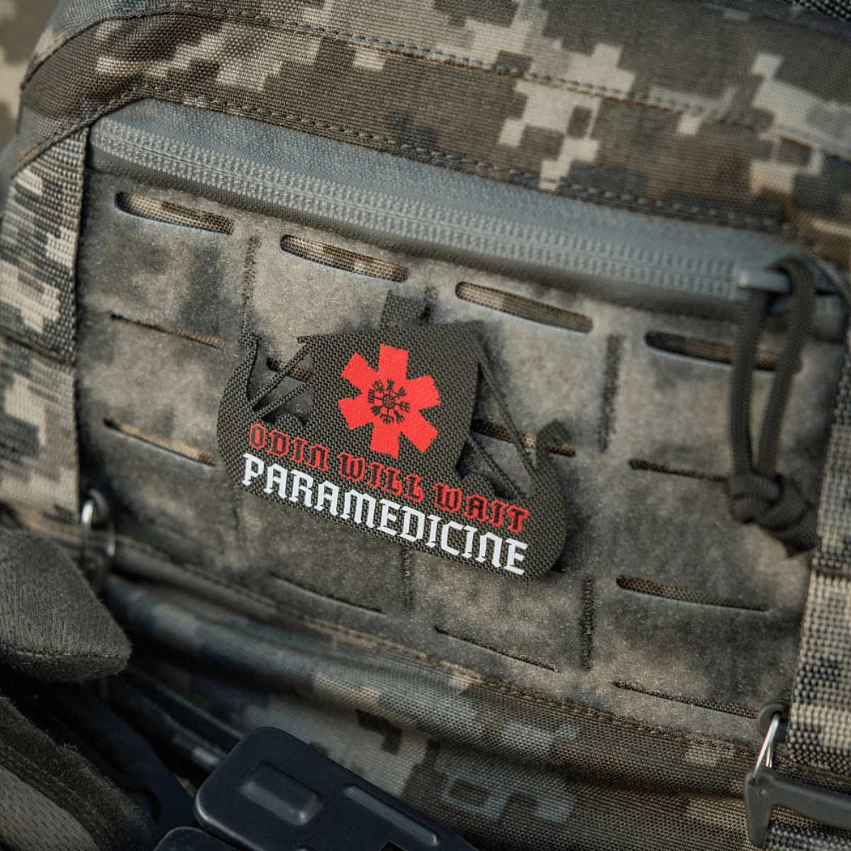 M-Tac Patch Viking Evac på en camouflagevåbentaske med teksten "Odin Will Wait Paramedicine".