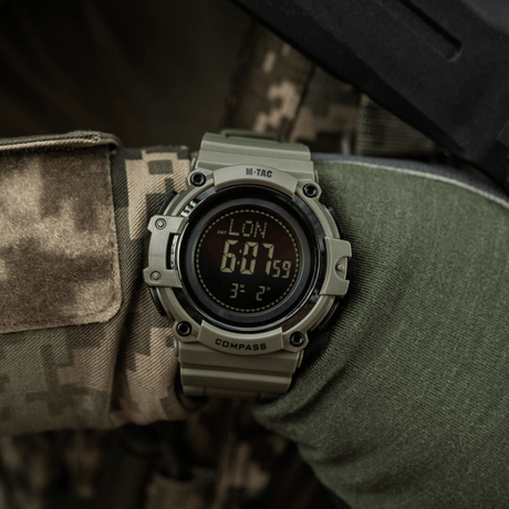 M-Tac Tactical Watch with Compass 2233 worn by a person in camouflage, suitable for outdoor activities with LED light and stopwatch.
