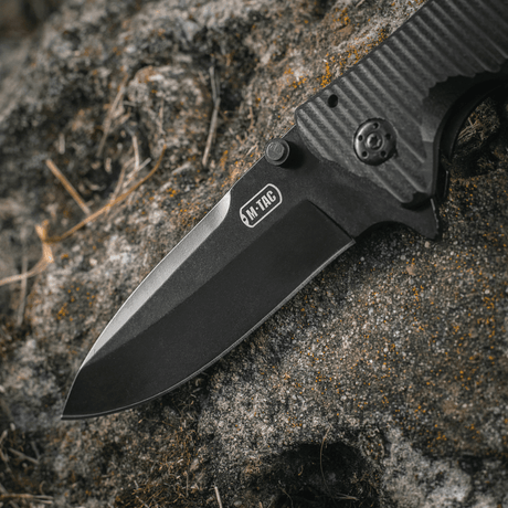 M-Tac Outdoor & Military folding knife - Type 7 with black‑coated stainless steel blade on a rock surface.