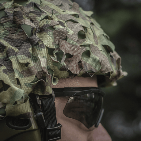 M‑Tac Vilha Hjelmcover Elite i Multicam-camouflage på en person, klar til at beskytte hjelmen mod snavs og slid under udfordrende forhold.