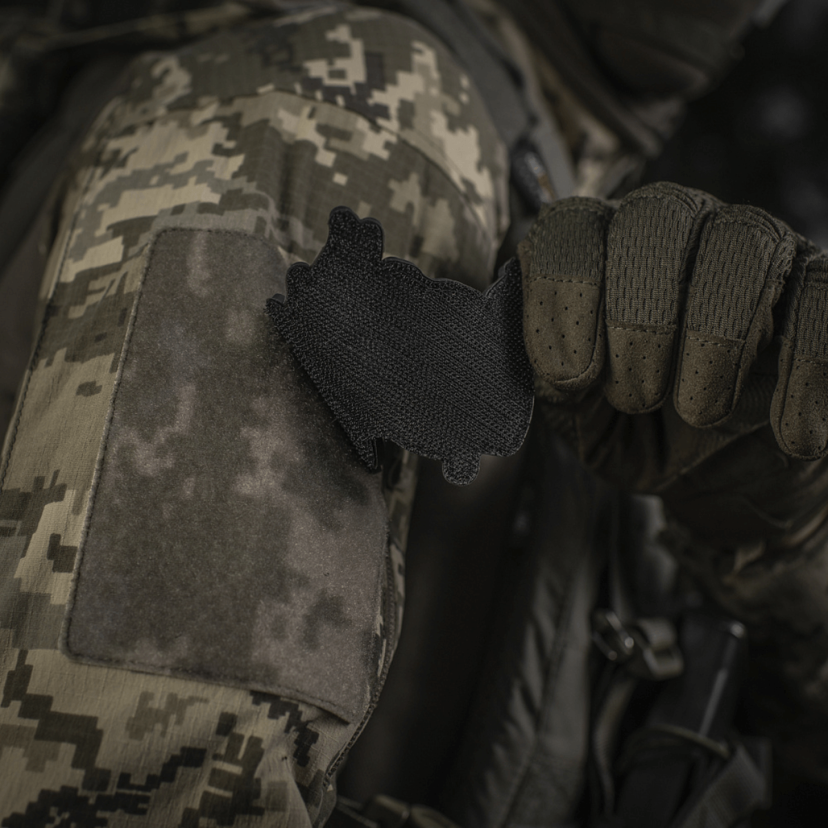 Soldat i camouflagejakke fastgør M‑Tac Patch Baba-Yaga Vertical på ærme med velcro.