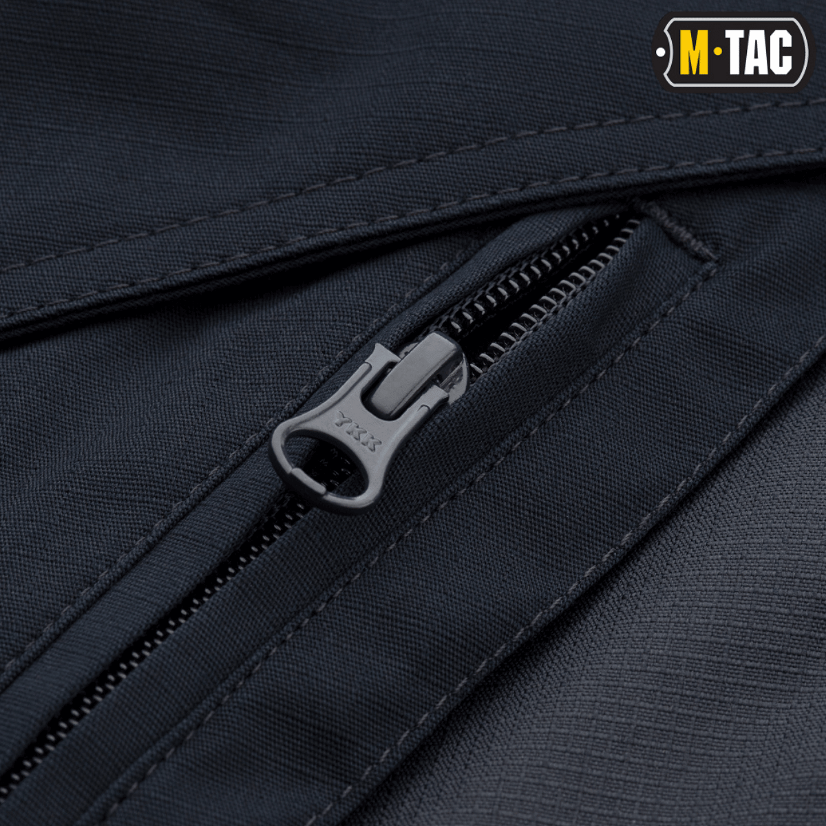 Nærbillede af lynlås på M-Tac Taktiske Bukser Aggressor Gen. II Flex med slidstærkt rip-stop stof og Teflon-belægning.