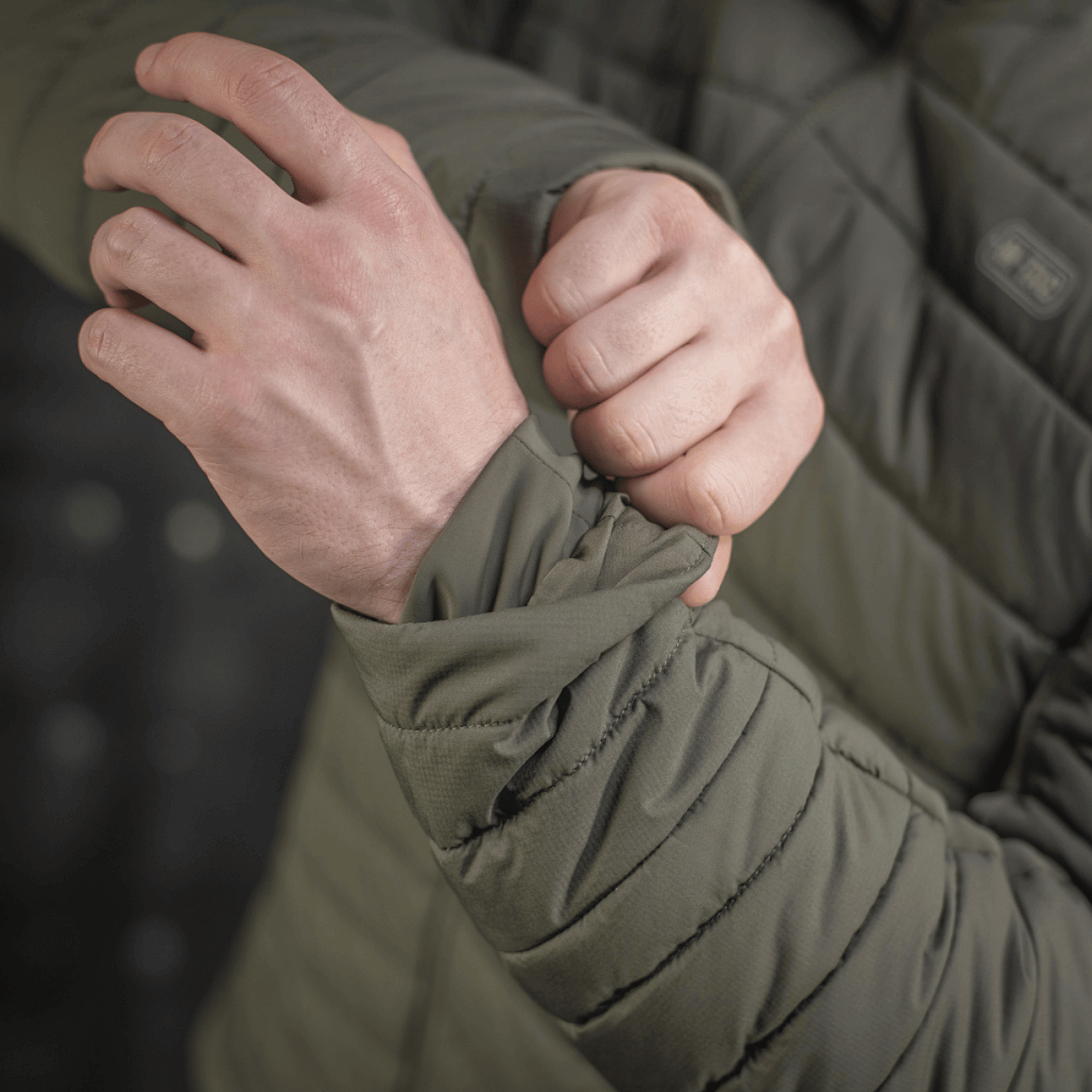 Nærbillede af person, der justerer ærmet på en M-Tac Jarl Jakke i åndbart Toray nylon til mellemsæsonens komfort og varme.