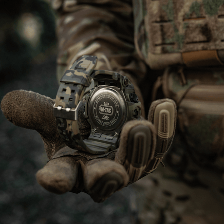 M-Tac Tactical Watch 2037 in camouflage design, water-resistant up to 5ATM, held by a gloved tactical hand in a forest setting.