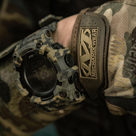 M-Tac Tactical Watch 2037 with rugged design, ideal for outdoor and tactical activities, shown on camouflage clothing against a nature-colored background.