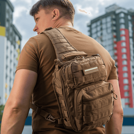 Man with a tactical backpack equipped with M-Tac Patch Flag 25x80 Mini Squares in an urban environment. Patch adds style and functionality.