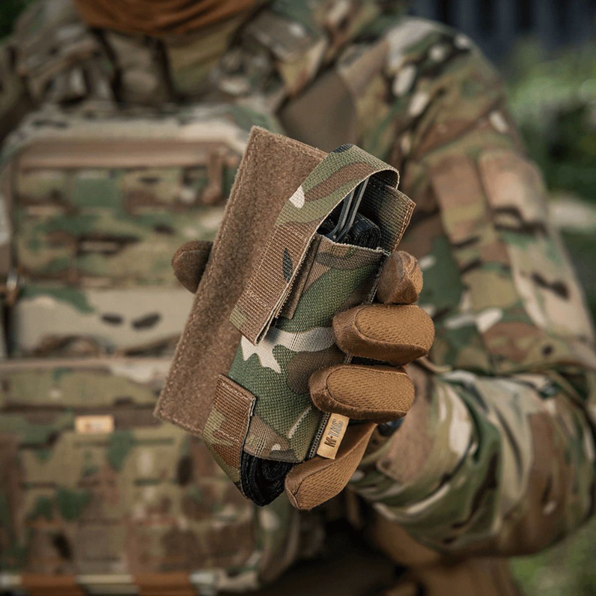 M-Tac Tourniquet Pouch Elastisk VELCRO Gen.II i camo-detaljer, monteret på en taktisk vest til hurtig adgang til C-A-T tourniquet.