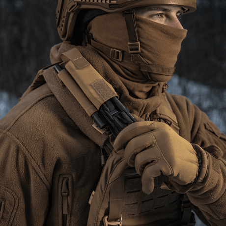 Person iført taktisk tøj med M-Tac Elastisk Tourniquet Pouch Molle Gen.III monteret på skulderen i vinterlandskab
