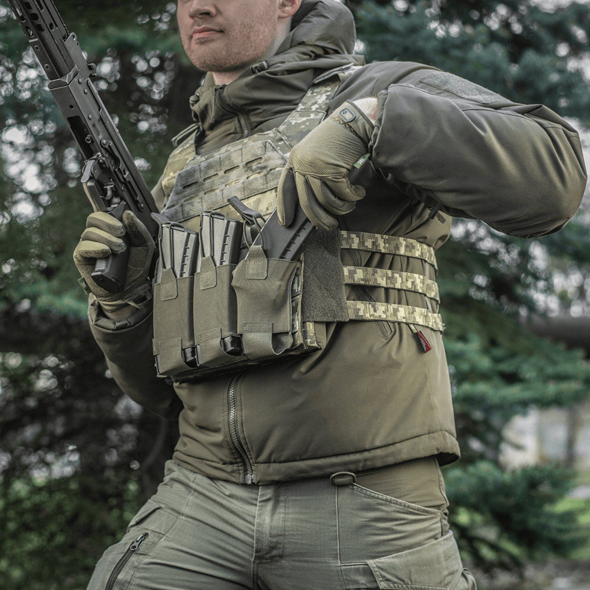 M‑Tac Elastisk Triple Magazine Pouch Elite monteret på taktikervest med tre magasiner, designet til hurtig adgang og sikker opbevaring.