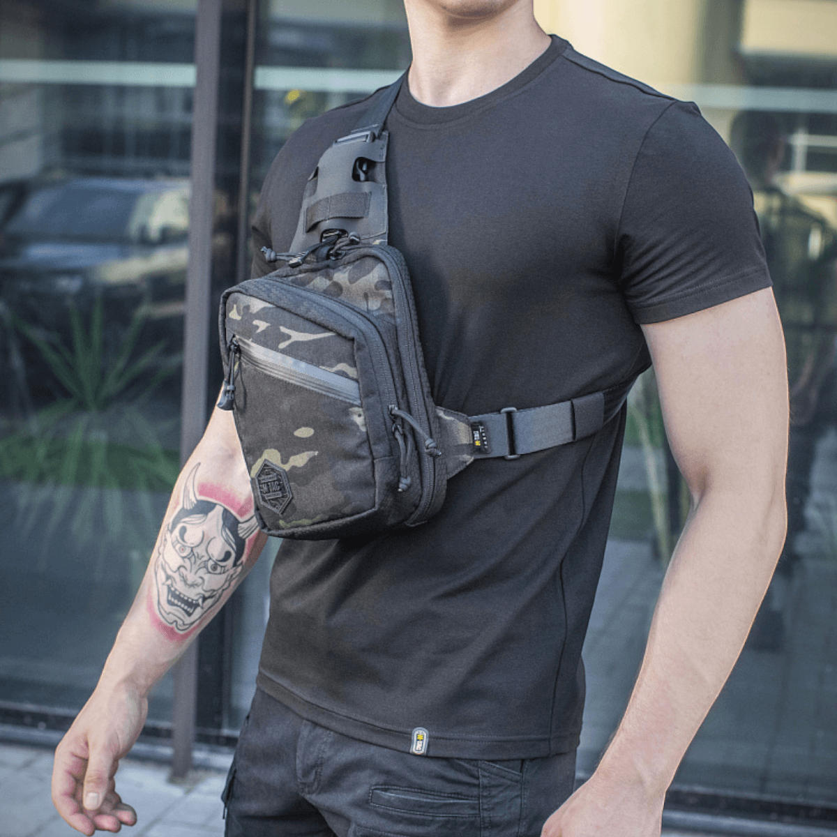 M-Tac Sling Pistoltaske Elite Hex båret af en mand iført sort t-shirt, viser taske detaljer og justerbar skulderrem.