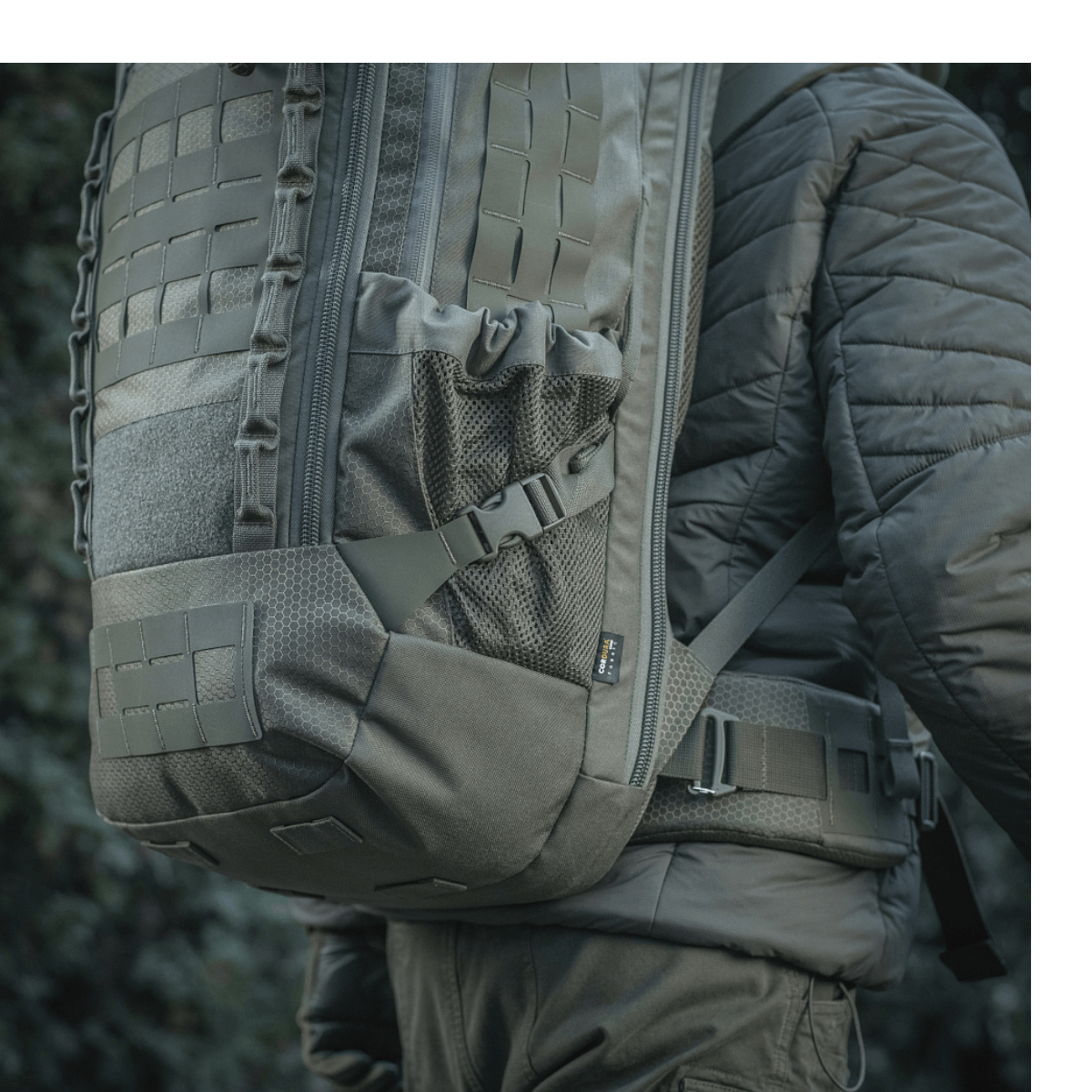 M-Tac Rygsæk Large Elite Hex Gen. IV bæres af en person, viser taskens stilfulde look og holdbare materialer som Cordura 500D og Hex 1000.