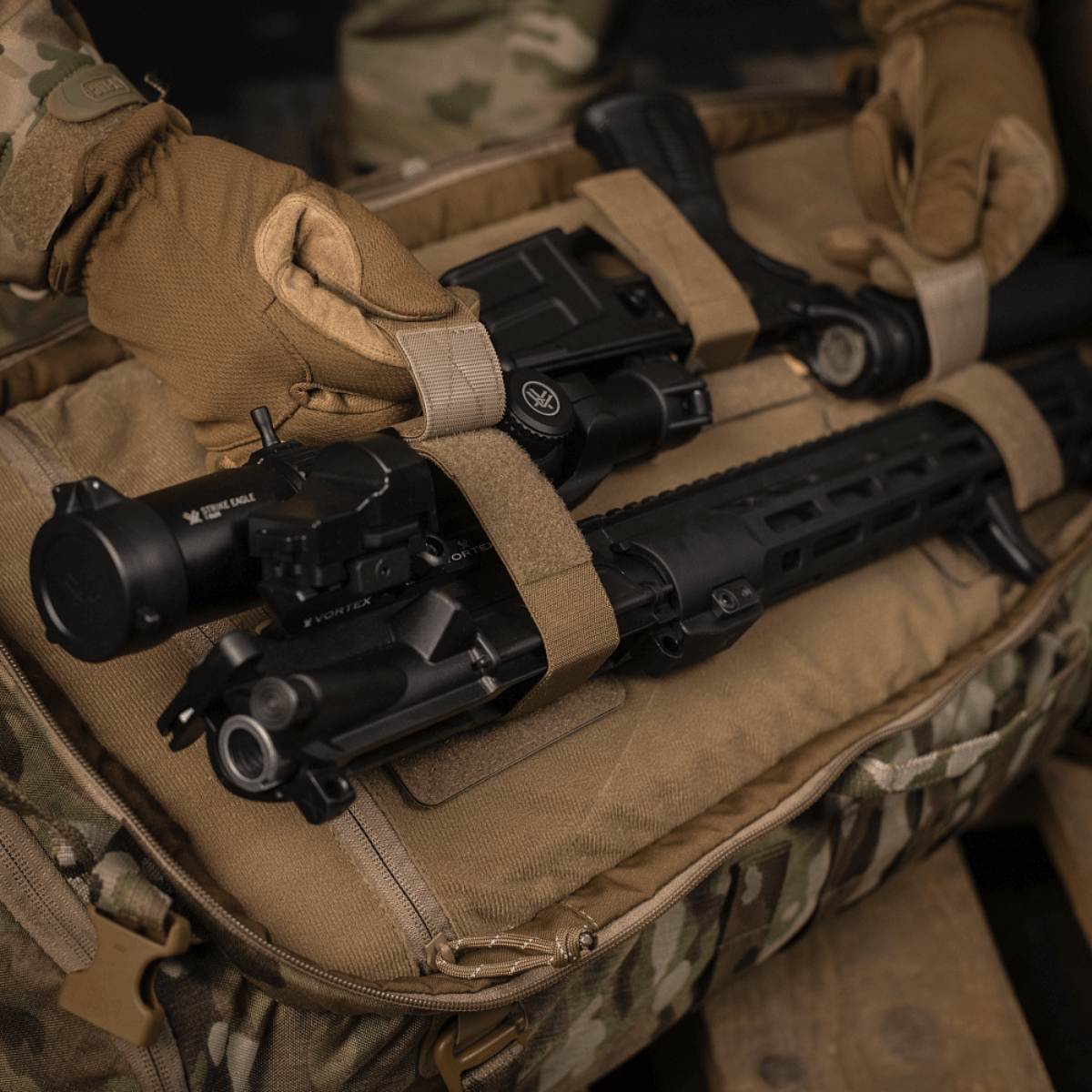 M‑Tac Indlæg til Rygsæk (3 stk) holder fastgjort AR-15 med Velcro-panel i en camouflage rygsæk, klar til sikker transport.