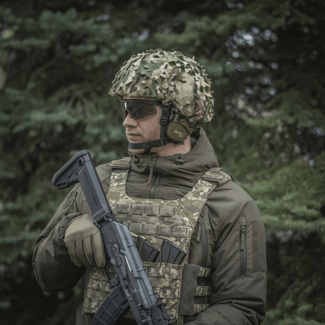 Soldat iført M‑Tac Vilha Hjelmdæksel Elite med multicam-camouflage i skovområde