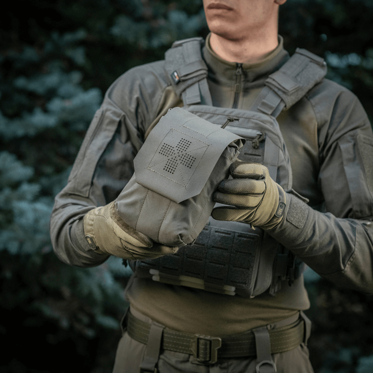 Person holder M‑Tac Medic Pouch Vertical Large Elite i slidstærkt Cordura, ideel til førstehjælpsudstyr og hurtig adgang.