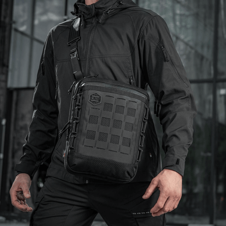 M-Tac Tablet Bag Laser Cut Hex i sort med Laser Cut MOLLE, bæret af en person, velegnet til EDC, dokumenter og tablet-opbevaring.