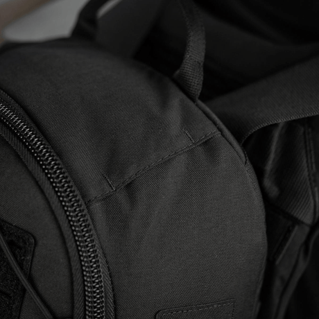 Nærbillede af sort rygsæk med lynlås og polstrede stropper, der fremhæver detaljerne i teksturen og syningerne i den robuste taske.
