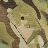 Nærbillede af camouflage stof med to knapper, viser detaljeret syning og mønsterdesign.