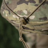 Detalje af camouflage stof med snørelukning og knap, set tæt på