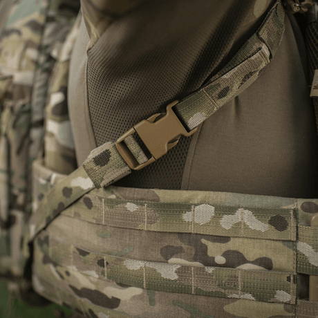 Nærbillede af en camoufleret rygsækrem med en plastikspænde, der tilsluttes til en taktisk vest.
