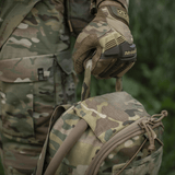 Militærperson i camouflageuniform med taktisk rygsæk, griber håndtag i skoven